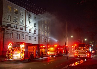 Water flies out of the window of a 4th floor apartment as firefighters dowse a fire at 446 King Street in London, Ont. on Friday March 27, 2020. One person was taken to the hospital with unknown injuries from the fire that began around 8:00pm.  Derek Ruttan/The London Free Press/Postmedia Network