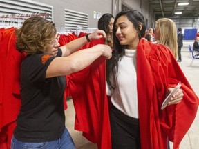 Mangot Kaur Hunjan, who is graduating with an Advanced communication degree gets some help with her graduation gown from Melissa Tower, who works in their registrars office, on the first day of Fanshawe College's fall convocation held at the Agriplex in London on Wednesday November 6, 2019.