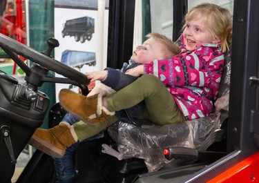 Julianne Burgin, 3, of Forest heaves mightily on her little brother Thomas, 20 months,  trying to haul him onto the driver's seat of a farm vehicle on the first day of the London Farm Show at the Western Fair Agriplex. 
Their mom, Allison Burgin, said the farm show "is like a free amusement park for the kids," and they come every year. "It's a family affair."
Mike Hensen/The London Free Press