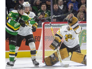 Knights forward Connor McMichael lunges to try to deflect a high shot past Sting goalie Benjamin Gaudreau while being checked by Eric Hjorth during the first period of their OHL game  Friday March 6, 2020, at Budweiser Gardens. Mike Hensen/The London Free Press