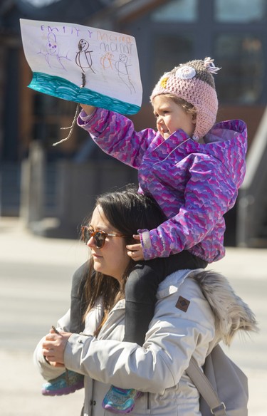 Mandy Gerhold from Delaware holds her daughter Emily Young, 4, who drew a picture of herself and her mom and other women standing together for the rally celebrating International Women's Day at Victoria Park before they marched to the London Library on Dundas Street in London. (Mike Hensen/The London Free Press)