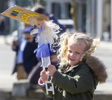 Maeve Vande Wetering, 3, of Delaware holds up an Elsa doll holding a sign saying "Women Rising" for the rally celebrating International Women's Day at Victoria Park in London. (Mike Hensen/The London Free Press)