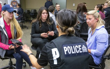 London police Const. Jean Hodgert talks with Tena Berdan, of London, and Teagan Horne and Katie Curtis of Stratford during a women's recruiting open house at the London Police headquarters on International Women's Day. (Mike Hensen/The London Free Press)