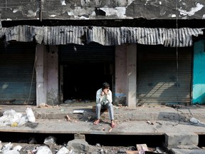 A man sits in front of burnt out properties owned by Muslims in a riot affected area following clashes between people demonstrating for and against a new citizenship law in New Delhi, India, March 2, 2020. REUTERS/Danish Siddiqui