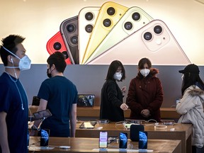 Apple staff and customers, wearing facemasks to protect against the COVID-19 coronavirus, are seen on the shop premises in Beijing on Feb. 22, 2020.