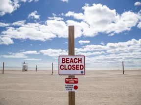 Signs declaring the beach closed  as one stating "Restricted area. No trespassing under penalty of the law," have been attached to a post that normally would hold on side of a volleyball net on Port Stanley's main beach. Everyone seems to be abiding by the order as not a soul was on the sand on Friday, April 10, 2020. (Derek Ruttan/The London Free Press)