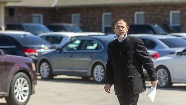 Pastor Henry Hildebrandt of the Church of God in Aylmer walks among his church goers, all buttoned up in their vehicles. Hilldebrand railed against churches not being considered essential, and people who serve the devil during an old Testament laden sermon Sunday equating his fight against the church closings as being a David and Goliath battle.  Photograph taken on Sunday May 3, 2020.  Mike Hensen/The London Free Press/Postmedia Network