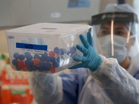 A laboratory technician wearing full PPE (personal protective equipment) holds a container of test tubes containing live samples taken from people tested for the novel coronavirus, at a new Lighthouse Lab facility dedicated to the testing for COVID-19, at Queen Elizabeth University Hospital in Glasgow on April 22, 2020. - The laboratory is part of a network of diagnostic testing facilities, along with other Lighthouse Lab sites in Milton Keynes and Cheshire, that will test samples from regional test centres around Britain where NHS staff and front-line workers with suspected Covid-19 infections have gone to have swabs taken for testing. (Photo by Andrew Milligan / POOL / AFP) (Photo by ANDREW MILLIGAN/POOL/AFP via Getty Images)