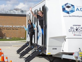 Registered nurse Ishy Misir, left, and X-ray technician Spring Robinson wave Thursday from one of the trailers that staff at South Huron Hospital in Exeter will begin using to rest and recharge during their long shifts. The trailers are part of a larger grassroots initiative in the town that also offers RVs for health workers who want to isolate from families during the pandemic so they don't pass on the illness. (Derek Ruttan/The London Free Press)
