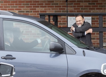 Church of God Pastor Henry Hildebrandt  gives a virtual hug to parishioners leaving  the church's parking lot in Aylmer, Ontario on Sunday April 26, 2020. In defiance of an order by the town's chief of police, the church held a drive-in service Sunday morning. Hundreds of parishioners sat in parked vehicles watching Hildebrandt on stage and listening to his sermon over their FM radios. Police video taped the event but have not yet laid charges. Derek Ruttan/The London Free Press/Postmedia Network