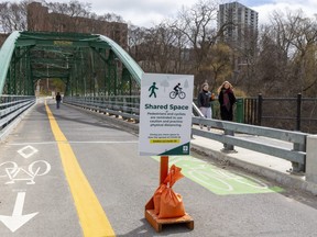 A city sign stating the need for social distancing has opened up the bridge to cyclists and pedestrians traveling in both directions with enough room for them to pass safely in London.  (Mike Hensen/The London Free Press)