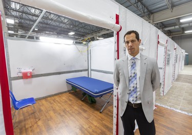 Ian Ball, a critical care doctor for London Health Sciences Centre, stands next to one of the rooms at the LHSC field hospital being constructed at the Western Fair District Agriplex in London on Tuesday. The 144-bed unit will treat patients who are on the mend from COVID-19 but not well enough to go home, said Ball. The unit can expand to 500 beds if the need arises. (Mike Hensen/The London Free Press)