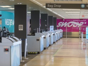 Empty lines of check-in desks for Air Canada, WestJet and Swoop at London International Airport. (Mike Hensen/The London Free Press)