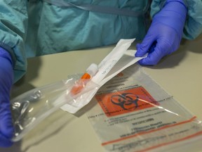 A sleeve containing a COVID-19 swab and container is opened at the Oakridge Arena assessment centre. The swab, which staff say is basically a large Q-tip, is inserted into the sinus for a sample, and then put in the container and a bag, and taken to a lab for testing. (Mike Hensen/The London Free Press)