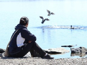 Hope Mott sits in solitude while enjoying the warmer temperatures on the shore of Ramsey Lake in Sudbury, Ont. on Friday April 24, 2020. (John Lappa/Postmedia Network)