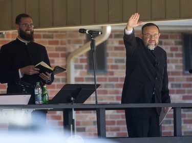 Pastor Henry Hildebrandt of the Church of God in Aylmer waves to his parishioners, all buttoned up in their vehicles.   (Mike Hensen/The London Free Press)