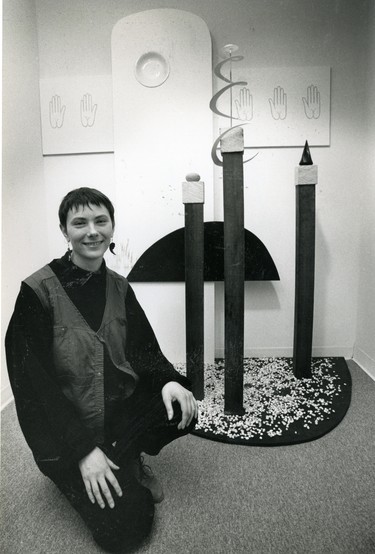 London artist Geri Binks kneels in front of a monument that forms part of her sculpture/painting/poetry installation at Centricity Gallery, 1989. (London Free Press files)