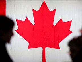 People are silhouetted in front of the Canadian national flag at the Palais des Congres in Montreal, Oct. 21, 2019.