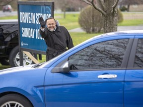 Pastor Henry Hildebrandt waves good-bye to parishioners following a drive-in service at The Church of God in Aylmer, Ont. on Sunday May 10, 2020. Parishioners listened on their FM radios as Hildebrandt delivered his sermon from a stage. (Derek Ruttan/The London Free Press)