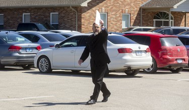 Pastor Henry Hildebrandt of the Church of God in Aylmer walks among his churchgoers, all seated in their vehicles. Photograph taken on Sunday May 3, 2020. Mike Hensen/The London Free Press/Postmedia Network