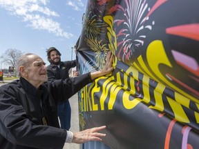 Bob Leff, who's been selling fireworks for 57 years, helps hold a fabric banner sign in place for his son Michael who is running the bang business now in London. The pandemic has forced the cancellation of big fireworks events on Victoria Day, but smaller, family celebrations can still go ahead. (Mike Hensen/The London Free Press)