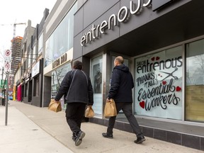 Two men brownbag it as they walk down a nearly deserted Richmond Street past the closed hair salon Entrenous in London on Friday. (Mike Hensen/The London Free Press)