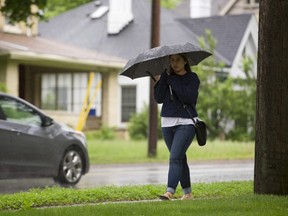 Daniella Navas of London walks along Richmond Street, tucked under her umbrella in a constant rain in London, Ont. on Sunday May 31, 2015. (File photo)