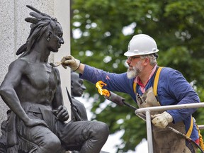 Alexander Gabov, an art conservator, applies hot wax to a statue at the Joseph Brant monument on Monday June 22, 2020 in downtown Brantford. It's part of a regularly scheduled monument maintenance program. Created by British sculptor Percy Wood and unveiled in 1886, the monument commemorates Joseph Brant and the Six Nations Confederacy for their dedicated service to the British Crown during the American Revolutionary War and the War of 1812. (Brian Thompson/Brantford Expositor)