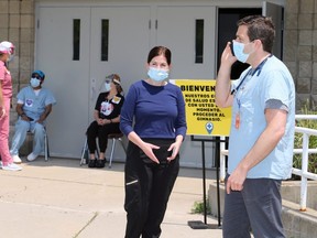 Dr. Ross Moncur, right, interim CEO Erie Shores HealthCare, and Kristin Kennedy, centre, vice president of patient services, prepare for the next group of migrant farm workers at the COVID-19 assessment centre at Leamington Kinsmen Recreation Complex Wednesday. (NICK BRANCACCIO/Postmedia Network)