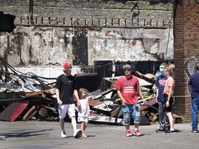 People walk past the charred remains of a pawn shop destroyed during last week's rioting on June 3, 2020 in Minneapolis, Minnesota. Protests marred by rioting and looting in some places erupted after Floyd died May 25 while in the custody of Minneapolis police.  (Photo by Scott Olson/Getty Images)