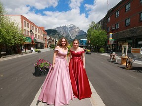 Alberta high school graduates Faith McLaughlin, left, and Katia Allan pose for what may be the most picturesque grad photos ever -- with mountains and Banff's pedestrian-only main street as a backdrop Thursday, June 18. (Gavin Young/Postmedia)