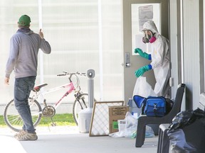 A man who just dropped of an air filter gives a thumbs up to someone in full PPE at Residence 2 at Greenhill Produce in Kent Bridge, Ontario. A sign on the door states "DO NOT ENTER! This bunkhouse is under quarantine." Dozens of migrant workers that are housed in bunkhouses were diagnosed with COVID-19. (Derek Ruttan/Postmedia Network)