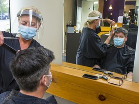 Hairstylist Linda Ouellet cuts Patrick Dompierre's hair on Monday as Salon Tok on Rue Montcalm in the Hull sector of Gatineau, Que., opens for business for the first time since the pandemic began. (Wayne Cuddington/Postmedia Network)