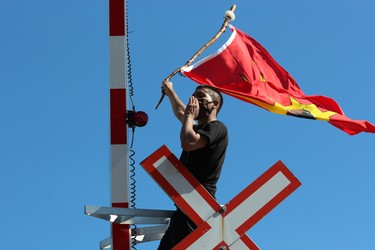 A demonstrator waves a flag from atop a railway cross light during the Black Lives Matter rally in London on June 6, 2020. DALE CARRUTHERS / THE LONDON FREE PRESS