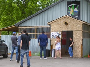 People gather to buy cigarettes at shops on Carriage Road just outside of Oneida of the Thames First Nation southwest of London.  Some of these sites also sell marijuana and were raided by the OPP on Thursday. (Mike Hensen/The London Free Press)