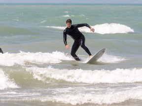 Curtis Parker of Etobicoke gets a short ride on the waves at Port Stanley's main beach south of London, Ont. on Wednesday June 10, 2020.  The beach remains closed, so the surfers had to walk out from the base of the pier, to avoid using the beach. All though the beach closed signs are gone, walkers and parents sitting with their children, were told to leave the beach by an active beach patrol, who said they didn't know when the beach would reopen, but it wouldn't be this weekend. (Mike Hensen/The London Free Press)