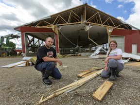 Tom Pettit and his daughter Maddie, 14 kneel among the damage to their dairy barn which had the back end blown right off in a tornado strike last night just south of Belmont. Maddie, who says she's been terrified of tornado's since seeing her mother watch "Twister," was the first person to see the funnel, but her dad was slow to believe her, until he saw the debris cloud around his neighbours home. Photograph taken on Thursday June 11, 2020. (Mike Hensen/The London Free Press)