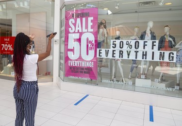 Amoy Barton directs co-worker Mandy McDonald of Urban Planet ras they hang 50% off banners before the opening of their store in White Oaks Mall in London, Ont.  Photograph taken on Friday June 12, 2020.  Mike Hensen/The London Free Press/Postmedia Network