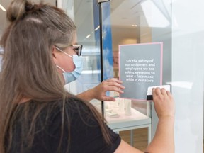 Becca Wade of Pandora puts up signs encouraging customers to wear masks in their store in White Oaks Mall for Max Martin  in London, Ont.  Photograph taken on Friday June 12, 2020.  (Mike Hensen/The London Free Press)