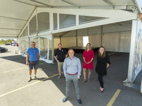 Tim Parker, left, of Big Top Tents, Rob Aitken of Music Central, Curt Collins of Collins Clothiers, Rosemary Nyhoff of Time 4 Flowers and Heather MacEachern of HRM are part of the business team behind a drive-thru prom experience being offered to COVID-confined area high schoolers in a big tent behind Collins' London location on Adelaide Street South this week. Bookings start at $50, organizers say.  (Mike Hensen/The London Free Press)