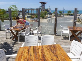 Kate Wuytenburg, left, and Taylor Majerle, two servers at the Growling Gator in Grand Bend, prepare the patio for patrons as it reopens Friday. Majerle says they're "super excited. It's been a slow summer." Wuytenburg is frustrated "really good weather" as already passed without the restaurant being allowed to open. The Growling Gator will have its usual patios as well as a new patio in its parking lot that will fit 19 tables. The beach, meanwhile, will reopen on Monday. (Mike Hensen/The London Free Press)