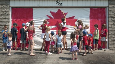 CANADA DAY 2012: Kids from Linda Van Meerbergen's daycare, along with friends from around the neighborhood, paint a giant Canadian flag on the garage of her Farnham Road home in London's Westmount neighbourhood.  An annual tradition, kids big and small all got their hands dirty while kicking off their Canada Day celebrations. CRAIG GLOVER The London Free Press
