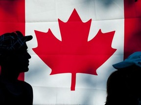 People are silhouetted against  a Maple Leaf flag as they walk through Harris Park during Canada Day celebrations in London on Sunday July 1, 2012. (Free Press file photo)