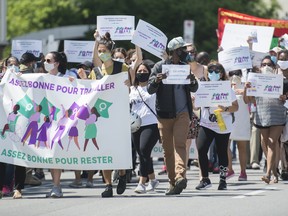 People demonstrate outside Prime Minister Justin Trudeau's constituency office in Montreal earlier this month, calling on the government to give residency status to migrant workers as the COVID-19 pandemic continues. The sign reads "Good enough to work here; good enough to stay here." (The Canadian Press)