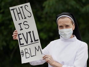 Sister Quincy Howard of the Dominican order of nuns in Washington protests with a sign reading "This is Evil #BLM" as President Donald Trump's visits the nearby Saint John Paul II National Shrine while protests continue against the death in Minneapolis police custody of George Floyd, in Washington, D.C., U.S., June 2, 2020. (REUTERS/Kevin Lamarque)
