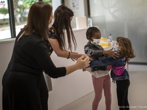 Teachers try to prevent the hug between classmate and friends Wendy Otin, 6, and Oumou Salam Niang, 6, as they meet during the first day of school after the lockdown, at a primary school in Barcelona, Spain, Monday, June 8, 2020. (Emilio Morenatti, The Associated Press)