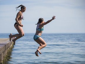 Madalin Malloy and her daughter Myla, 10, jump into the cool water of Lake Ontario at the Beach neighbourhood in Toronto on Tuesday. Ernest Doroszuk/Toronto Sun
