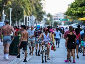 In this file photo a man rides a bicycle as people walk on Ocean Drive in Miami Beach, Florida on June 26, 2020. Florida has registered more than 15,000 new cases of coronavirus in a day, easily breaking a record for a US state previously held by California, according to official numbers published on July 12, 2020.  (Photo by CHANDAN KHANNA/AFP via Getty Images)