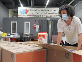 Maha Kheder, board member of the Canadian Iraqi House in London, helps pack food to be distributed to about 400 Arabic-speaking families struggling financially during the COVID-19 pandemic. (JONATHAN JUHA/The London Free Press)