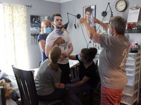 Abby Roby, right, congratulates her son, Tristan Roby, who was seriously hurt last summer in a hit-and-run crash, after managing to stand with the assistance of some of his care team during a therapy session. (JONATHAN JUHA, The London Free Press)